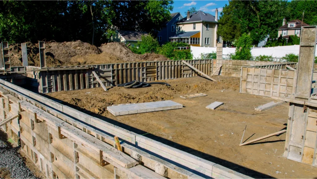 Un chantier de construction avec une fondation en béton et des murs en bois, illustrant différents types de fondations.