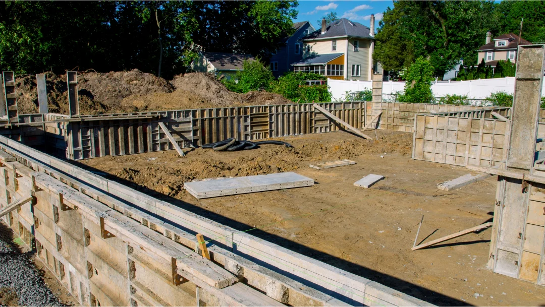 Un chantier de construction avec une fondation en béton et des murs en bois, illustrant différents types de fondations.