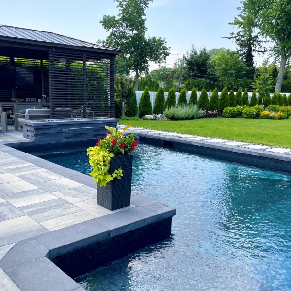 Une piscine entourée d'un gazebo et d'un espace patio, illustrant un aménagement extérieur élégant et relaxant.