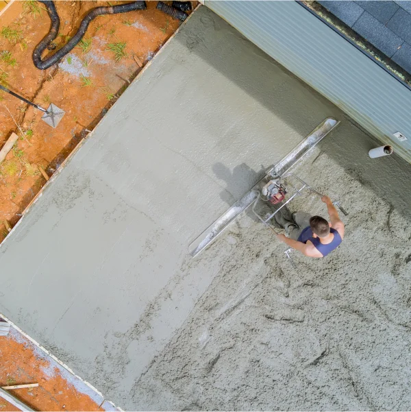 Un homme utilise un malaxeur à béton pour couler du béton, illustrant les différents types de fondations.