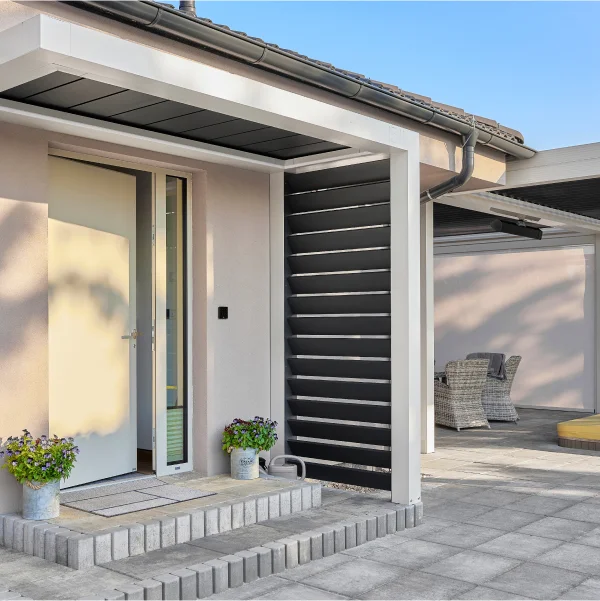 Une porte blanche ouverte sur un patio, mettant en valeur un aménagement extérieur accueillant et lumineux.